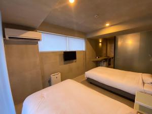 Habitación pequeña con 2 camas y ventana en maejima Hotel en Naha