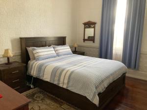a bedroom with a bed with a striped comforter and a window at Rose Cottage in Bunbury
