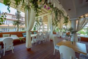 ein Restaurant mit weißen Stühlen, Tischen und Pflanzen in der Unterkunft Mia Cassa in Sweti Wlas
