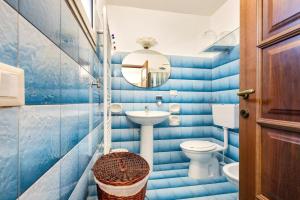 a blue tiled bathroom with a toilet and a sink at La Casa di Anna in Sava