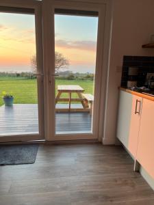 a kitchen with a sliding glass door with a table outside at MAESLLAN CABINS - 'Golwg Y Mor' in Cross Inn