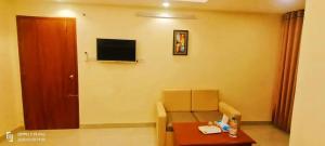 a room with a chair and a table and a television at Hotel Crown City in Chittagong
