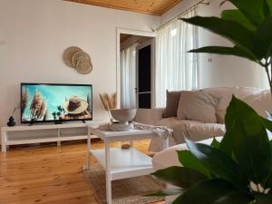 a white living room with a couch and a tv at Emerald in blue in Loutraki