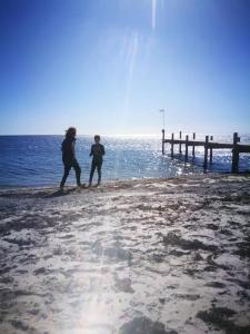 two people walking on a pier near the water at Fishermans Cottage Anno 1861 - Skåre Fiskeläge in Trelleborg