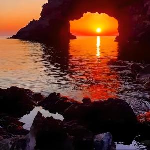 einen Sonnenuntergang über einem Wasserkörper in der Unterkunft Dammuso Pantelleria - Fiori D'Ossidiana in Pantelleria