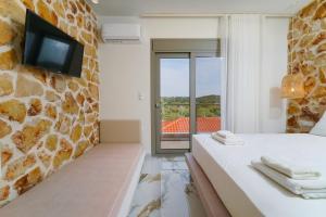 a bedroom with a bed and a tv on a stone wall at Athina Palace Luxurious Appartments in Potos