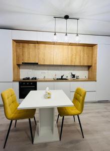 a kitchen with a white table and two yellow chairs at Apartament 1 camera Giroc in Giroc