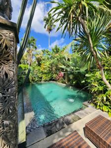 a pool in a tropical garden with palm trees at BUDA AMITABA in Ubud
