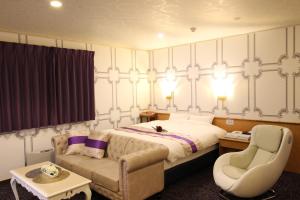 大仙市Hotel DOLPHIA-Adult Only的一间卧室，里面有一张床、一张沙发和一把椅子