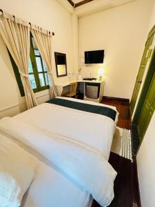 a bedroom with two white beds and a television at Barn Laos Luangprabang Hostel in Luang Prabang