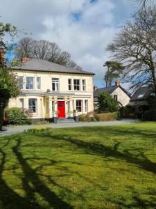 uma grande casa branca com uma porta vermelha em Holly Lodge em Pembrokeshire