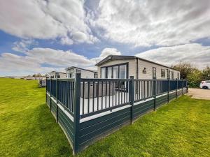 a house with a green fence in the grass at Luxury Lodge With Stunning Full Sea Views In Suffolk Ref 20234bs in Hopton on Sea