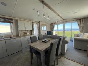 cocina y comedor con mesa y sillas en Luxury Lodge With Stunning Full Sea Views In Suffolk Ref 20234bs, en Hopton on Sea
