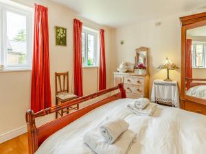 a bedroom with a bed with red curtains and a mirror at The Coach House in Aldington