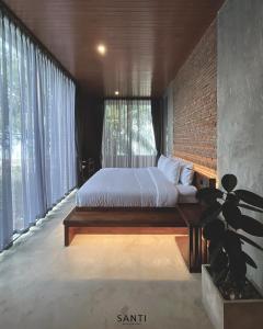 1 dormitorio con cama y pared de ladrillo en SANTI beach retreat, en Ban Rang Pla