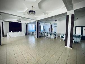 a large banquet hall with white tables and white chairs at Hotel Tata Si Fii in Bechet