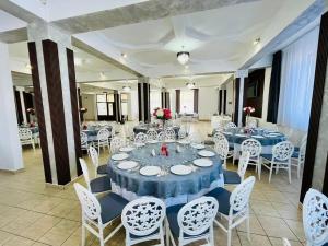 un comedor con mesas azules y sillas blancas en Hotel Tata Si Fii en Bechet
