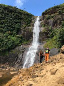 2 personnes marchant devant une cascade dans l'établissement Hotel mango tree nearest Adam's peak, à Nallathanniya