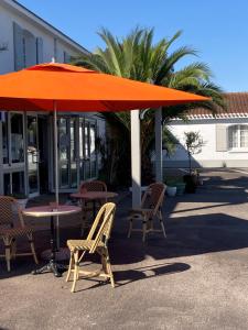 a table and chairs under an orange umbrella at Hôtel Le Gois in Beauvoir-sur-Mer