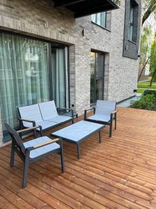 trois chaises et une table sur une terrasse en bois dans l'établissement Apartment w-Terrace I Air Condition I New building I Self Check-In, à Birštonas