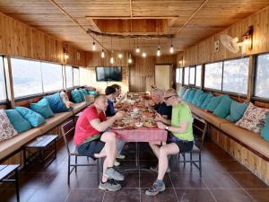Eine Gruppe von Menschen, die an einem Tisch sitzen und Essen essen. in der Unterkunft Matan Rural Lodge in Tufailah