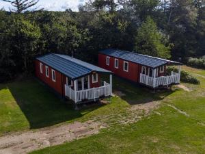 Dwa czerwone domy siedzą na trawniku w obiekcie Egtved Camping Cottages w mieście Egtved