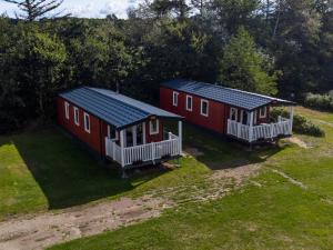 dos casas rojas están sentadas en un campo de hierba en Egtved Camping Cottages, en Egtved