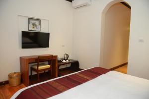 a bedroom with a bed and a desk and a television at Lux Hotel in Luang Prabang