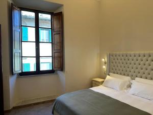 - une chambre avec un grand lit et une fenêtre dans l'établissement Tuscan Palace - Venturi, à Montepulciano