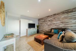 ein Wohnzimmer mit einem Sofa und einem TV in der Unterkunft VILLA L HORIZON 4 appartements avec piscine in Petite Île
