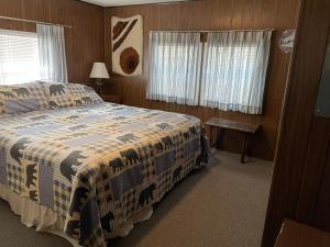 Schlafzimmer mit einem Bett, einem Tisch und Fenstern in der Unterkunft Grandma's Home in the Woods. Yellowstone in Island Park