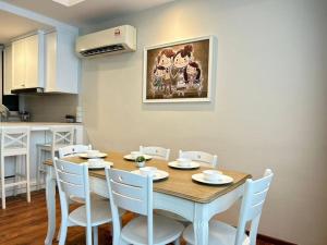 a dining room with a table and white chairs at Jeff & Ricky Homestay 82@Vivacity Megamall in Kuching