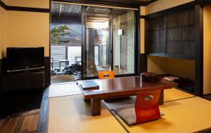 uma sala de estar com uma mesa de madeira e uma televisão em Bettei Soan em Minami Aso