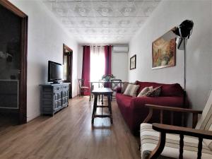 sala de estar con sofá rojo y TV en Casa Cervantes Toledo en Toledo
