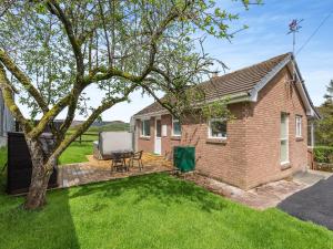 a brick house with a deck with a table and a chair at Cambrian Mountain View in Llanafan-fawr