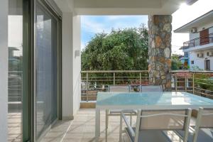 a glass table and chairs on a balcony at Athina Palace Luxurious Appartments in Potos