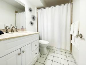a white bathroom with a toilet and a shower curtain at Waikiki Ilikai Marina in Honolulu