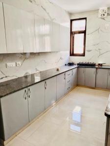 a large kitchen with white cabinets and a window at Divine India Service Apartment 2Bhk, 2A Saket in New Delhi