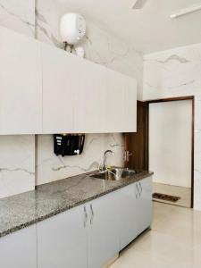 a kitchen with white cabinets and a sink at Divine India Service Apartment 2Bhk, 2A Saket in New Delhi