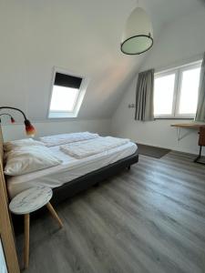 a bedroom with a bed and a table and windows at Penthouse DeLuxe in Oostkapelle