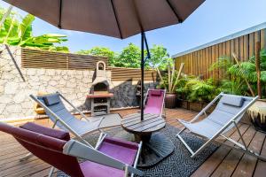 eine Terrasse mit Stühlen, einem Tisch und einem Sonnenschirm in der Unterkunft VILLA L HORIZON 4 appartements avec piscine in Petite Île