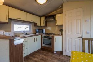 a kitchen with white cabinets and a stove top oven at Great 6 Berth Caravan For Hire At Southview Holiday Park Ref 33006m in Skegness