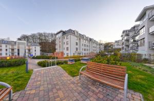 un banc de parc assis sur une passerelle en briques avec des bâtiments dans l'établissement Dom & House - Apartamenty Aquarius, à Sopot