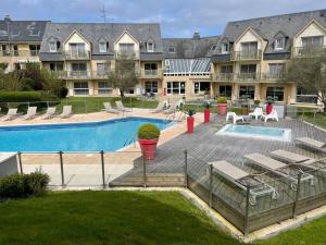 un grand complexe d'appartements avec une grande piscine dans l'établissement La terrasse du golf, à Port-en-Bessin-Huppain