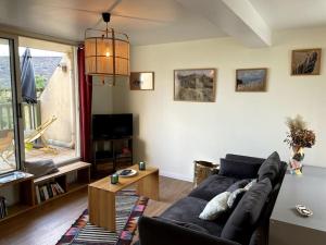 uma sala de estar com um sofá preto e uma mesa em La terrasse du golf em Port-en-Bessin-Huppain