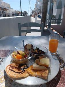 un piatto di prodotti per la colazione su un tavolo con un bicchiere di succo d'arancia di Lefkothea Hotel a Kamari