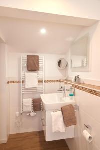 ein weißes Bad mit einem Waschbecken und Handtüchern in der Unterkunft Landgasthof Zum Sägwirt in Eggstätt