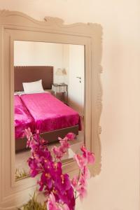 1 dormitorio con cama rosa y espejo en Emmeleia Accommodation by Maria Riga, en Ouranoupoli