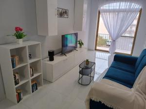 uma sala de estar com um sofá azul e uma televisão em Seagull Flats em Marsalforn