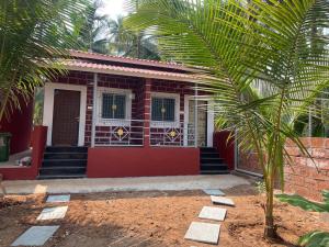 a red house with a palm tree in front of it at Sandcastle Cottages 2 AC - WiFi - SmartTV - Parking - Diveagar in Diveagar